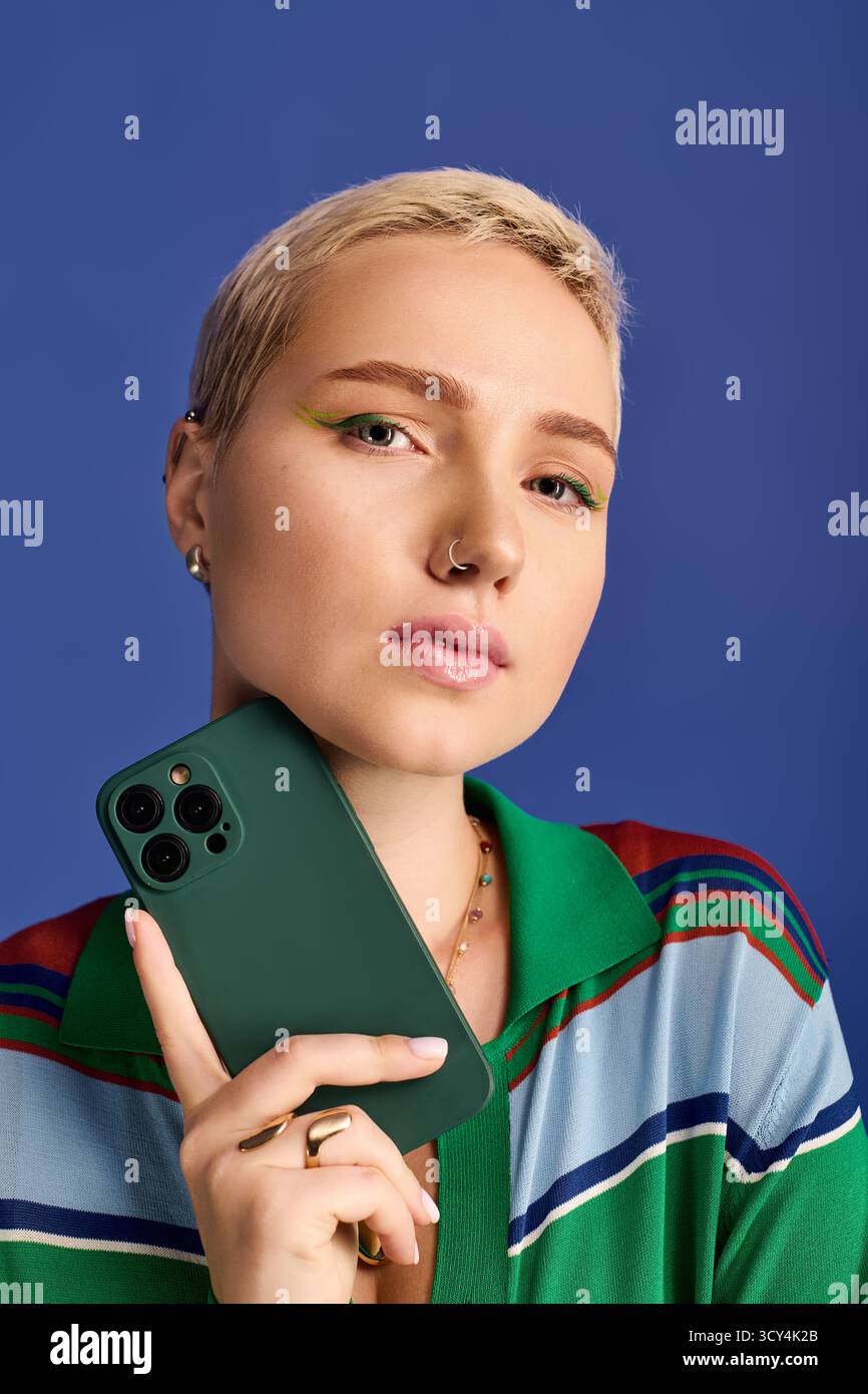 Una giovane donna elegante sfoggia il suo outfit moderno tenendo in mano uno smartphone, incarnando la moda. Foto Stock