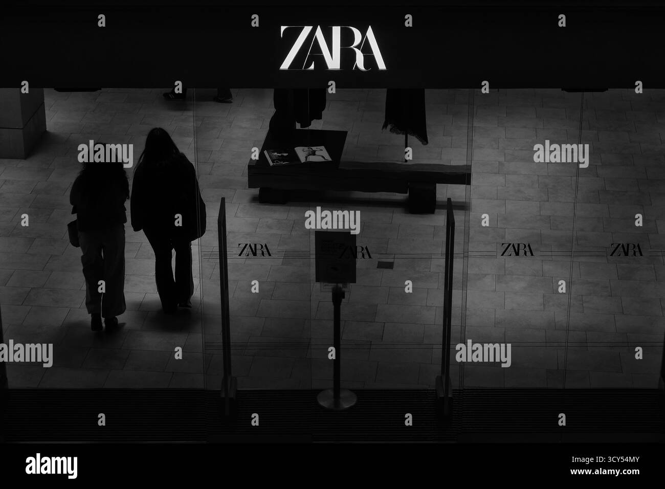 Immagine in bianco e nero di due acquirenti che entrano in un negozio Zara, catturando la vita moderna e la moda di strada in una composizione minimalista. Foto Stock Immagine in bianco e nero di due acquirenti che entrano in un negozio Zara, catturando la vita moderna e la moda di strada in una composizione minimalista. Foto Stock