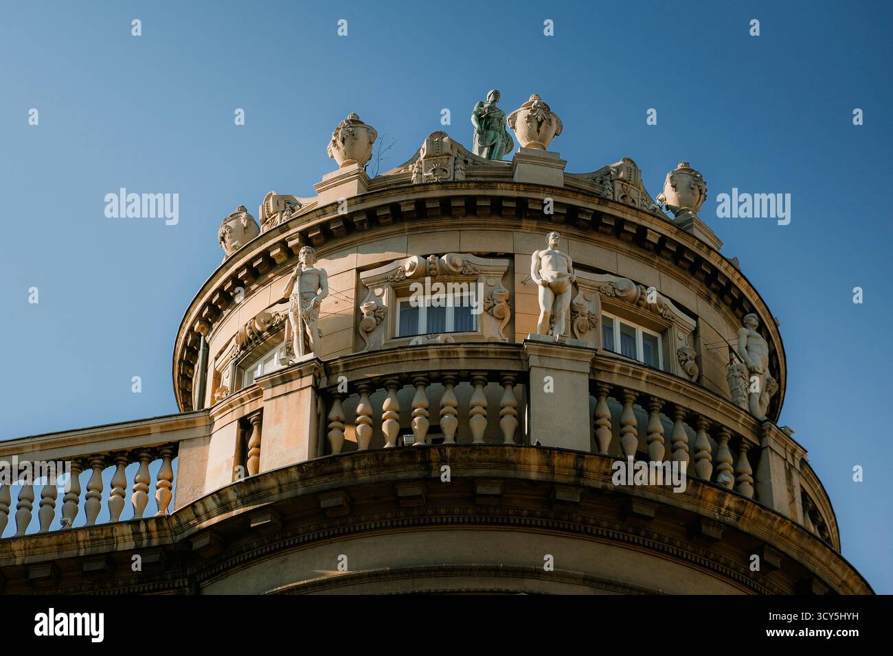 Dettaglio di un elegante edificio storico con sculture classiche e architettura ornamentale sotto un cielo azzurro Foto Stock