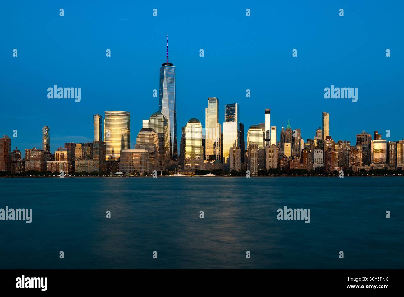 Lo skyline illuminato di New York nel centro di Manhattan, con edifici che brillano nella luce dorata della sera. Foto Stock