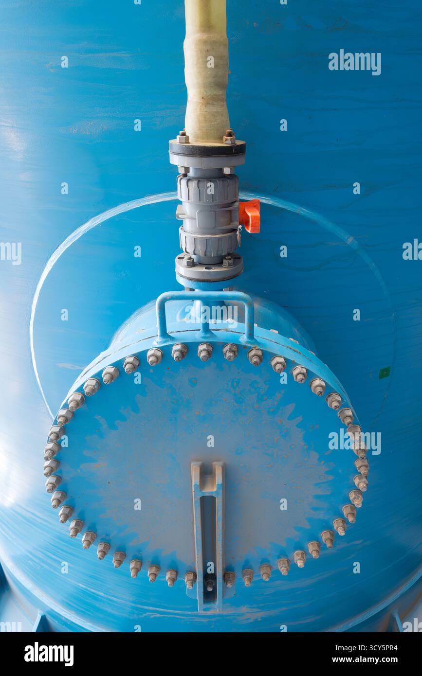 La base di un grande serbatoio dell'acqua blu in un impianto di desalinizzazione a osmosi inversa, con tubazioni e valvole dettagliate. Foto Stock