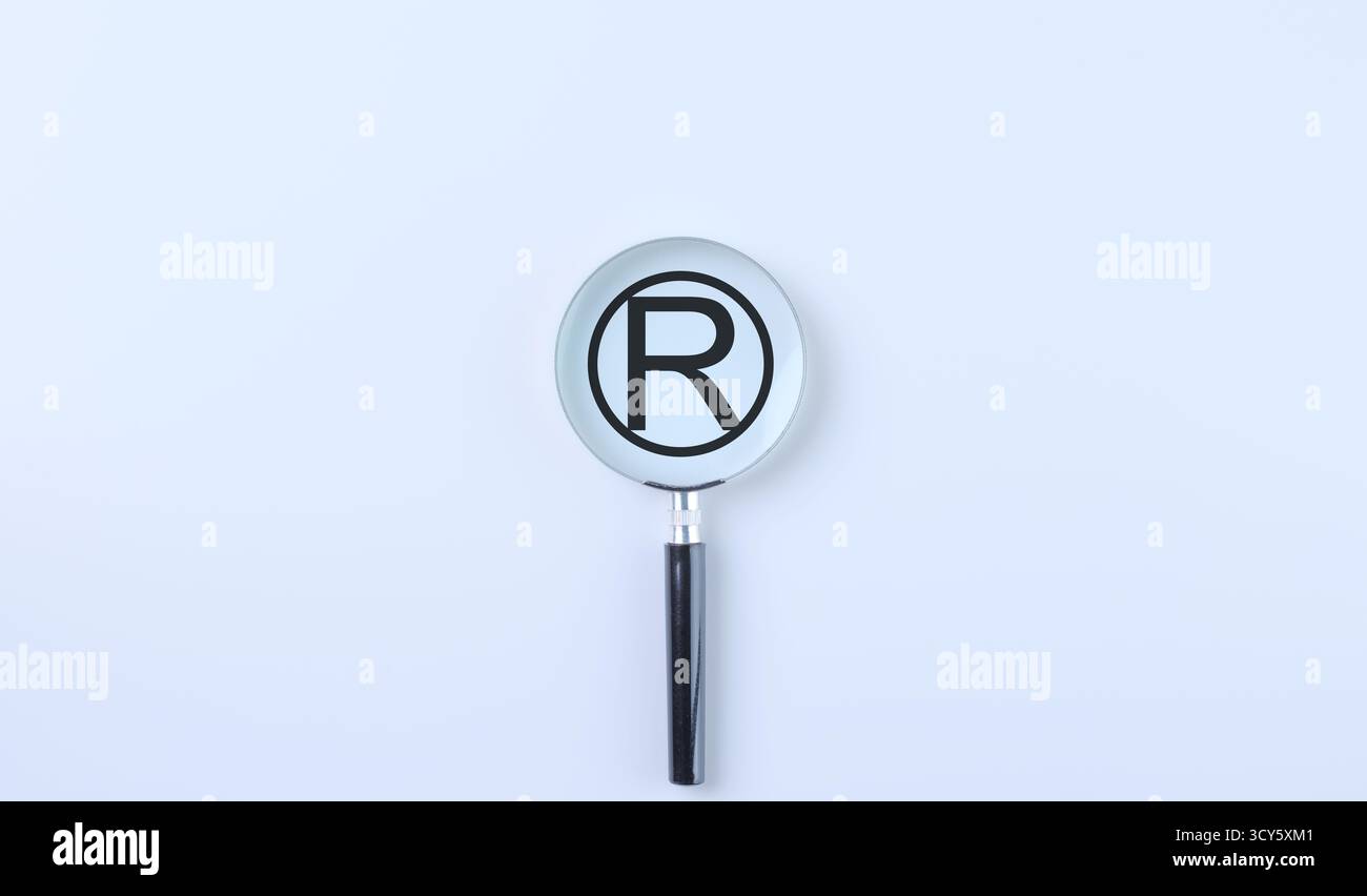 Registrazione del marchio Copyright Symbol. Una lente di ingrandimento si concentra su un simbolo di marchio registrato su uno sfondo bianco, Foto Stock