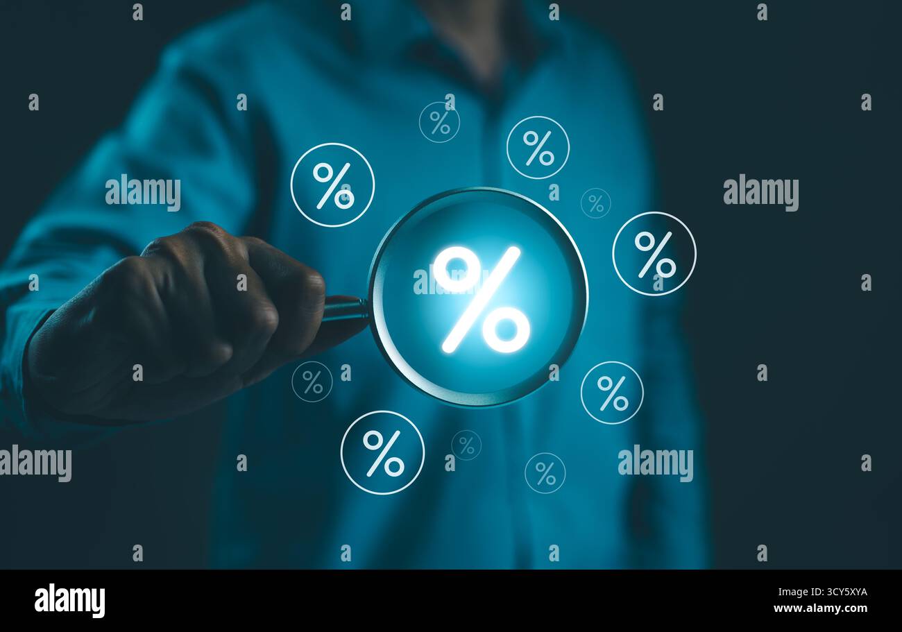 Concetto di tasso di interesse e dividendi. L'uomo d'affari ha una lente d'ingrandimento con simboli percentuali virtuali che la circondano, che rappresentano il tasso di interesse Foto Stock