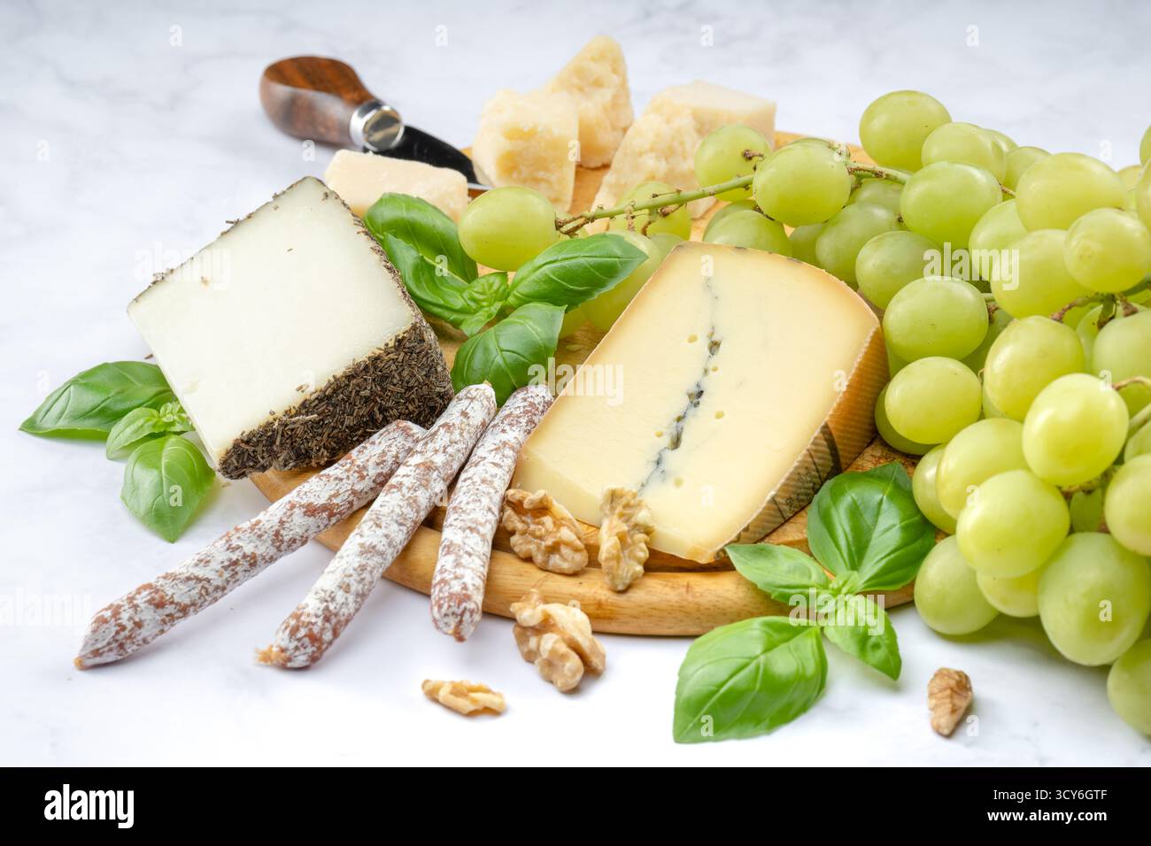 Stuzzichini di formaggio e uva serviti su un piatto di legno Foto Stock
