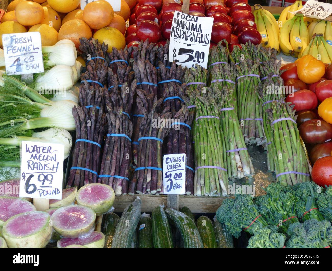 SEATTLE - 23 aprile 2025 - variopinta gamma di asparagi viola freschi, prodotti verdi e frutta vibrante organizzata ad arte al mercato agricolo locale Foto Stock