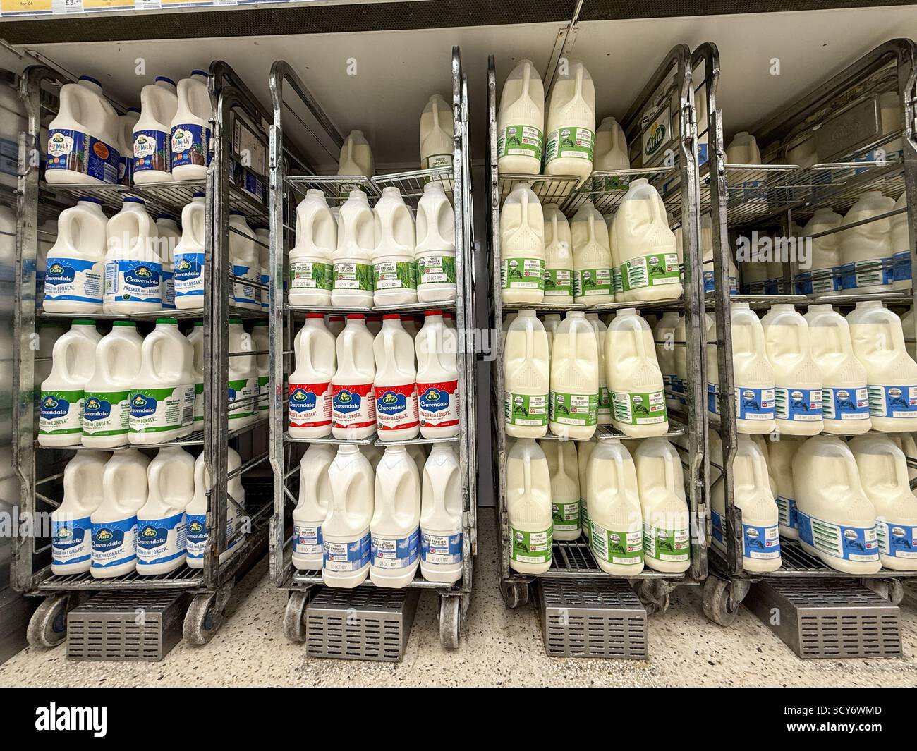 Più bottiglie di latte fresco sono impilate ordinatamente su scaffali e casse nel corridoio dei caseifici di un supermercato di Londra, pronte per l'acquisto da parte dei clienti. Foto Stock
