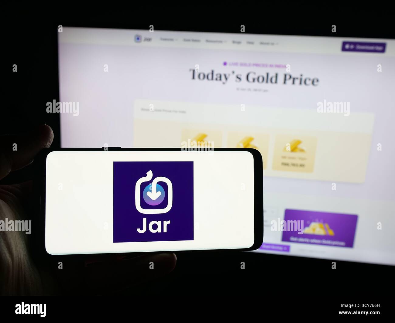 Stoccarda, Germania - 11-10-2025: Persona con smartphone con logo dell'app indiana Jar risparmia denaro in oro digitale sullo schermo di fronte al sito Web. Foto Stock
