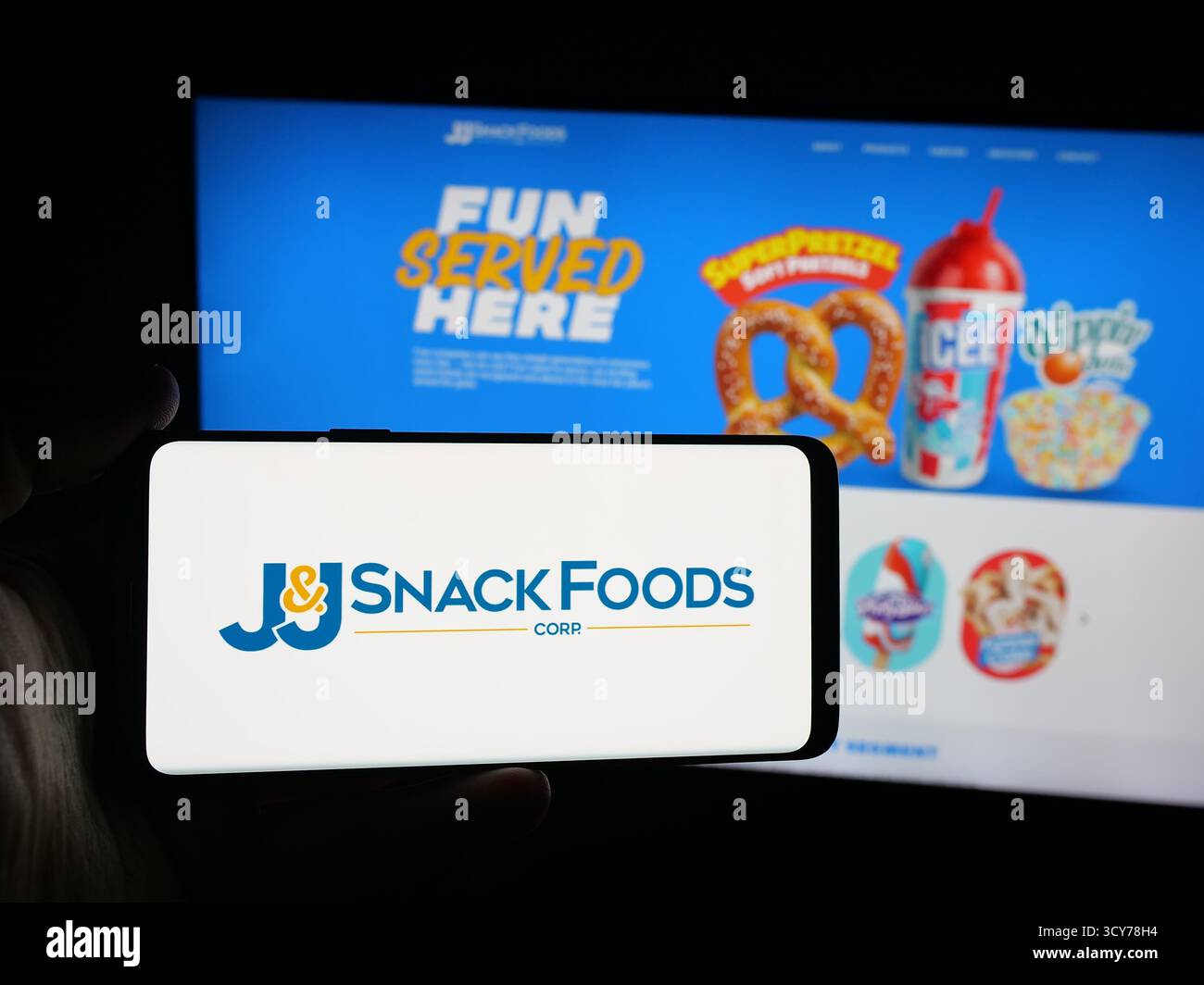 Stoccarda, Germania - 10-12-2025: Persona con smartphone con logo della società alimentare statunitense JJ snack Foods Corp. Sullo schermo di fronte al sito web. Foto Stock