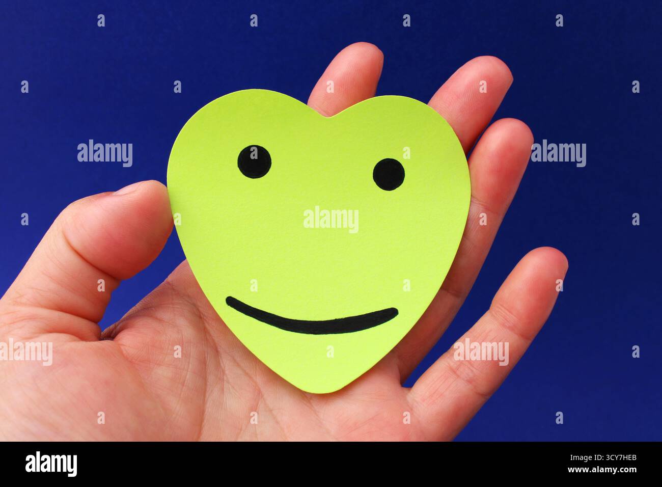 Mano che tiene un cuore con una faccia felice Foto Stock