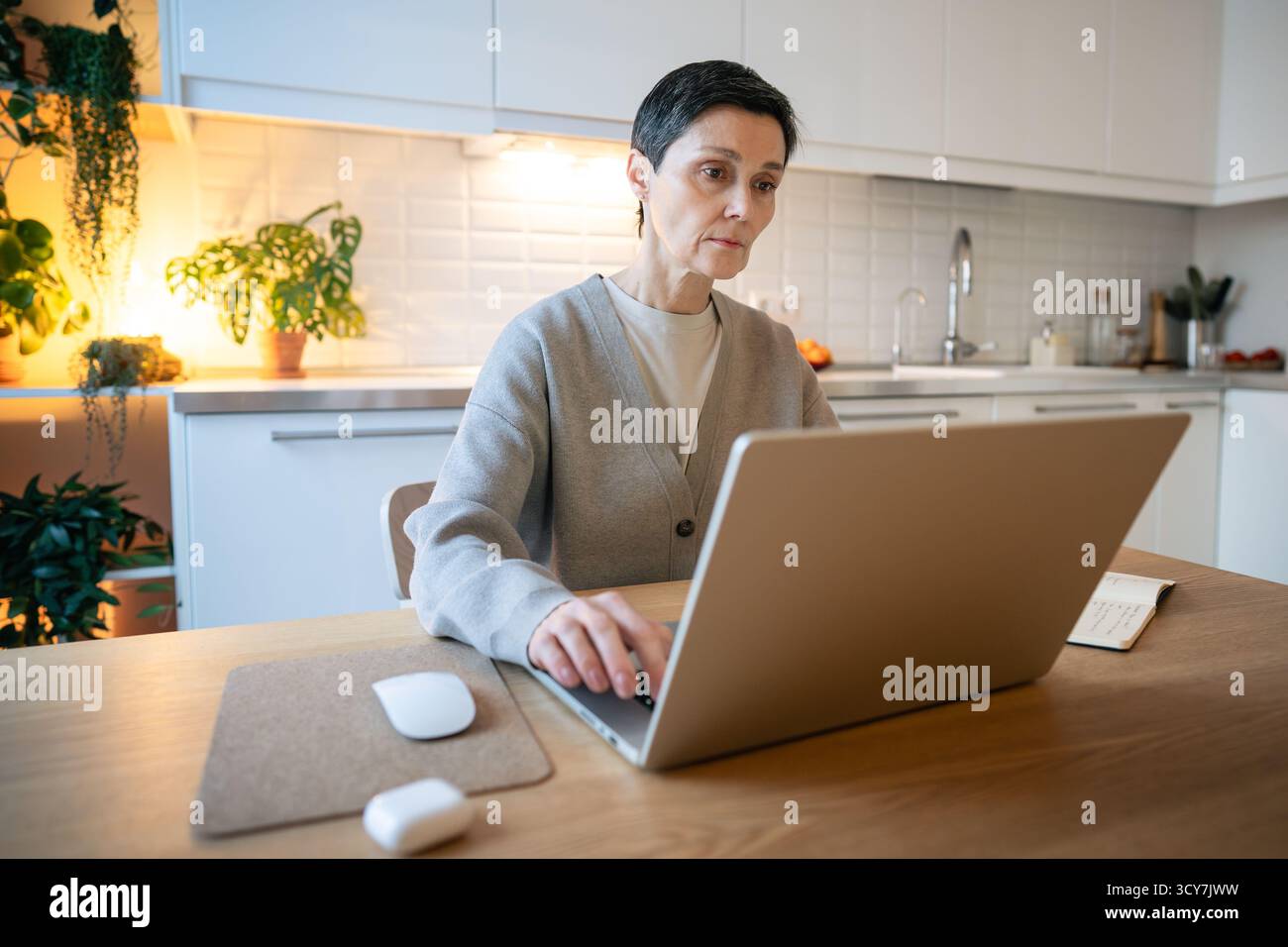 Donne attente che usano un notebook in cucina e cercano soluzioni. Bilanciare le scadenze, lavorare in remoto Foto Stock
