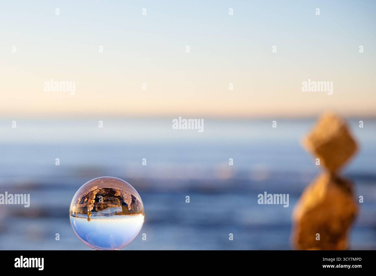 Lensball su una parete costiera che mostra una vista invertita di una costa rocciosa e acque calme a Lisbona, Portogallo, catturata vicino al tramonto con DOF poco profondo. Foto Stock