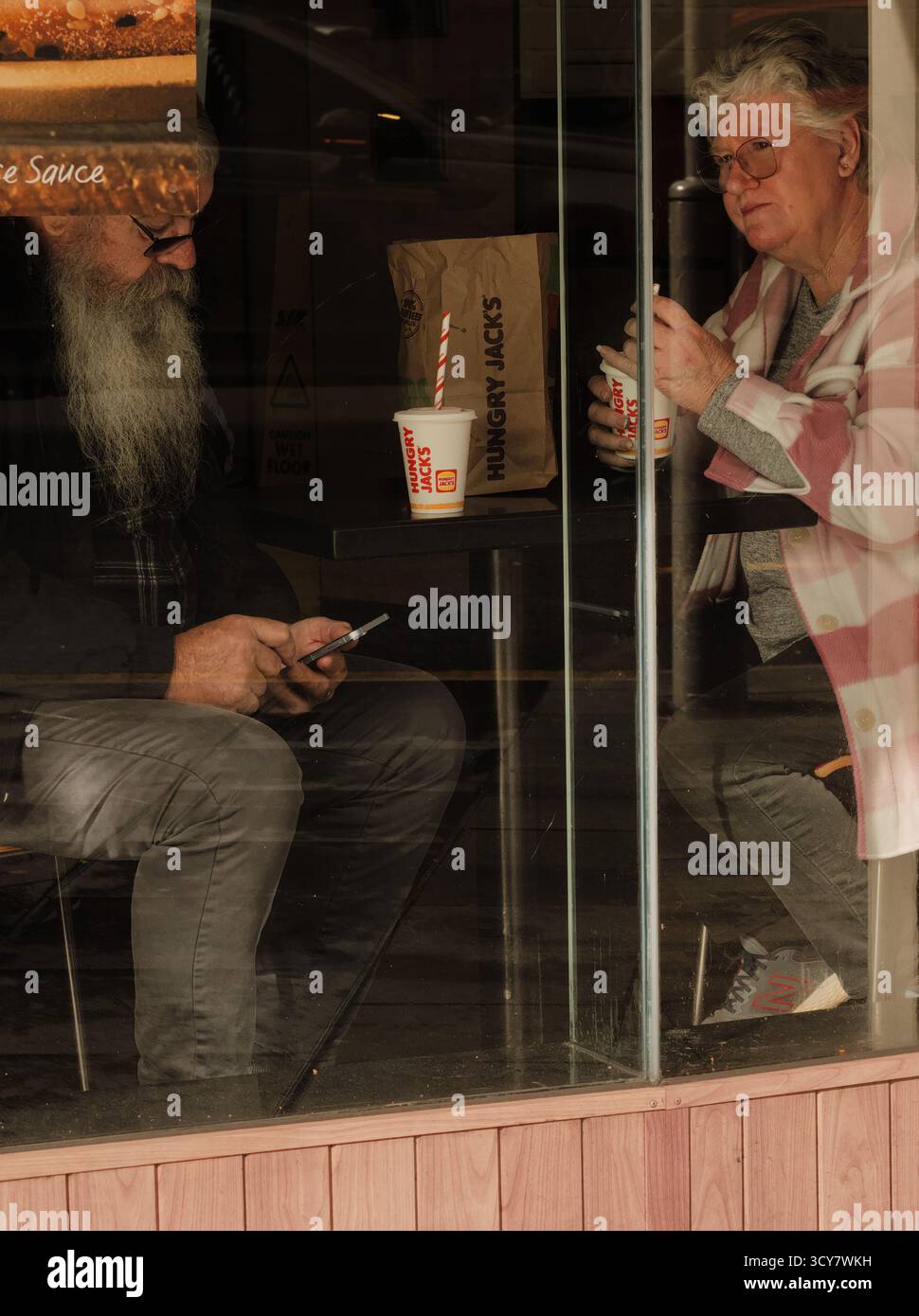 Foto a livello di strada di due adulti più grandi all'interno di un fast food; genuina, penosa, la vita di tutti i giorni. Foto Stock