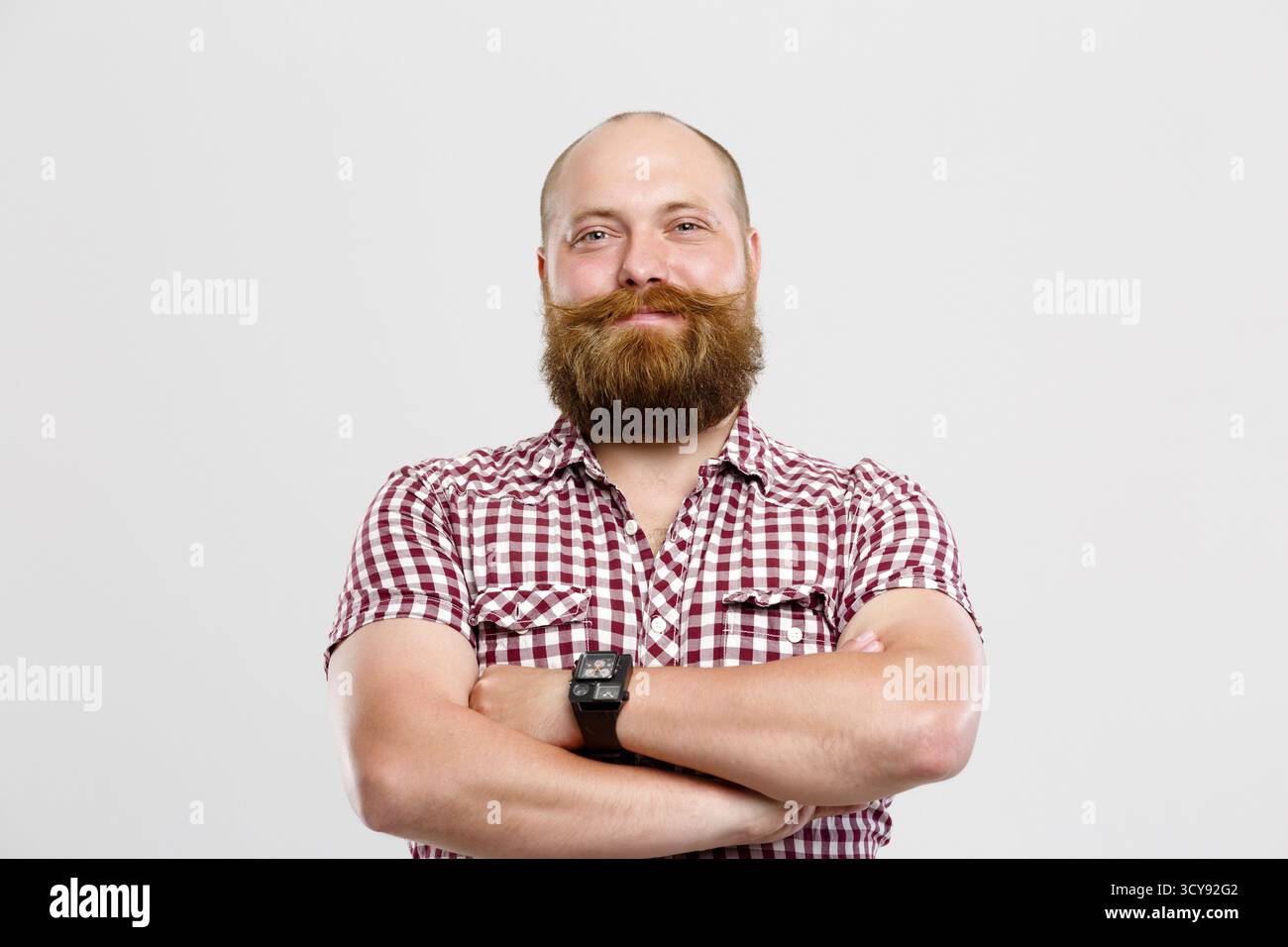 Uomo sorridente con la barba e baffi in plaid shirt vuoto su sfondo grigio Foto Stock