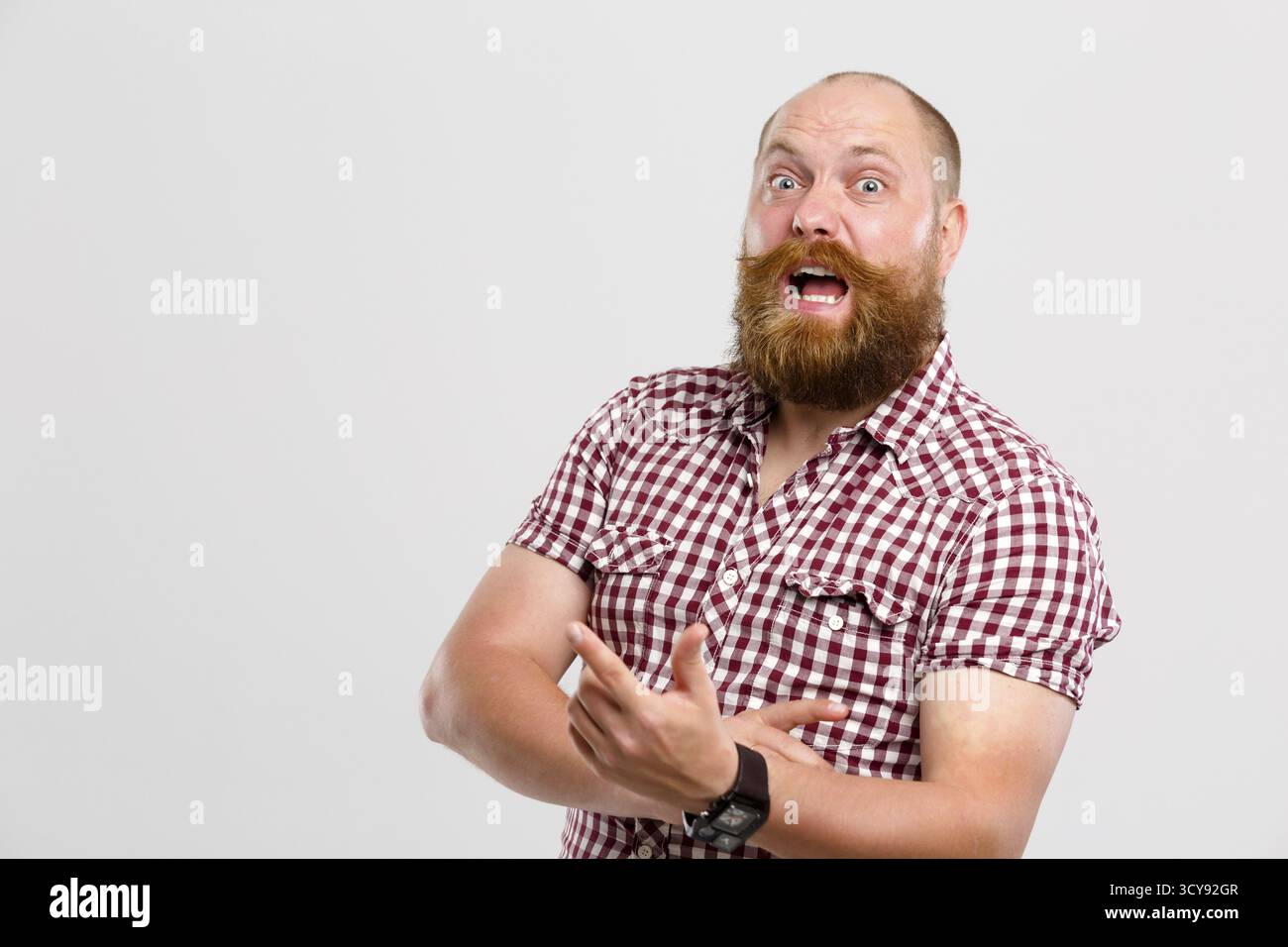 Uomo sorpreso con barba allo zenzero e baffi che puntano allo spazio vuoto, spazio pubblicitario Foto Stock