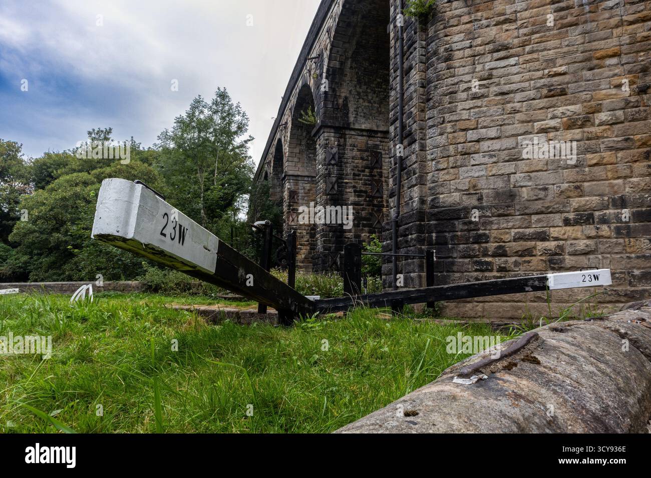 Cancello di blocco del canale in legno posto accanto ad un alto viadotto ferroviario in pietra con archi multipli Foto Stock