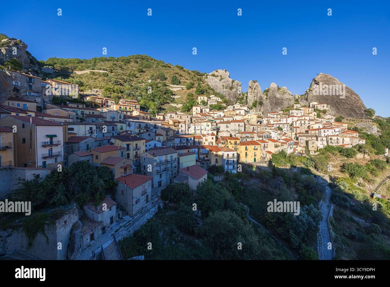 La luce del sole pomeridiano illumina Castelmezzano, con le sue case in pietra arroccate sulle aspre scogliere delle Dolomiti Lucane. Il tiepido bugiardo Foto Stock