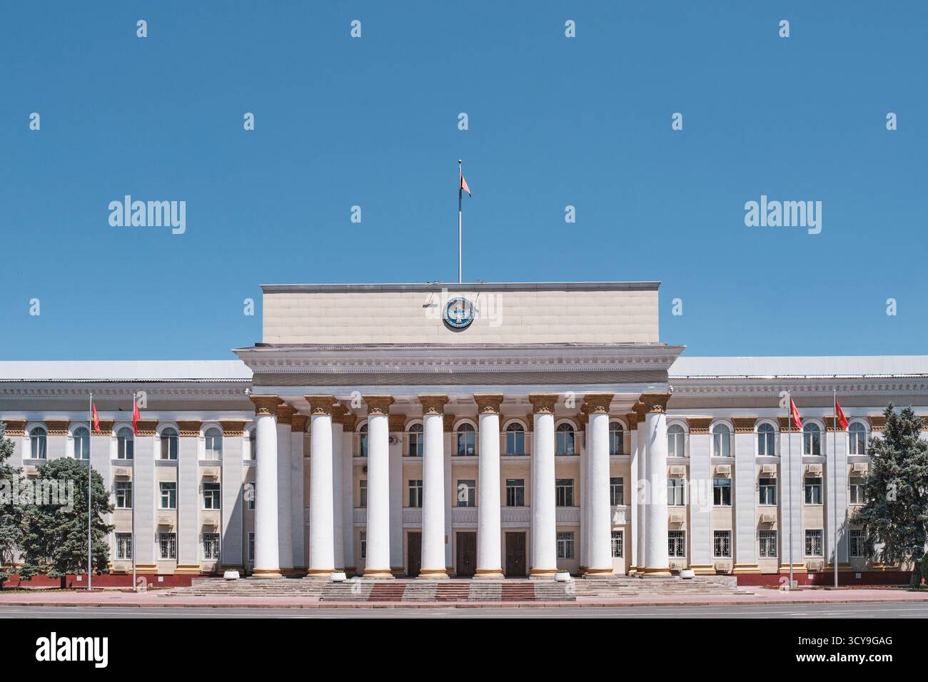 Kirghizistan, Bishkek - 12 luglio 2025: Imponente facciata dell'edificio del Ministero dell'economia e del commercio, con monumentali colonne bianche e coa nazionale Foto Stock