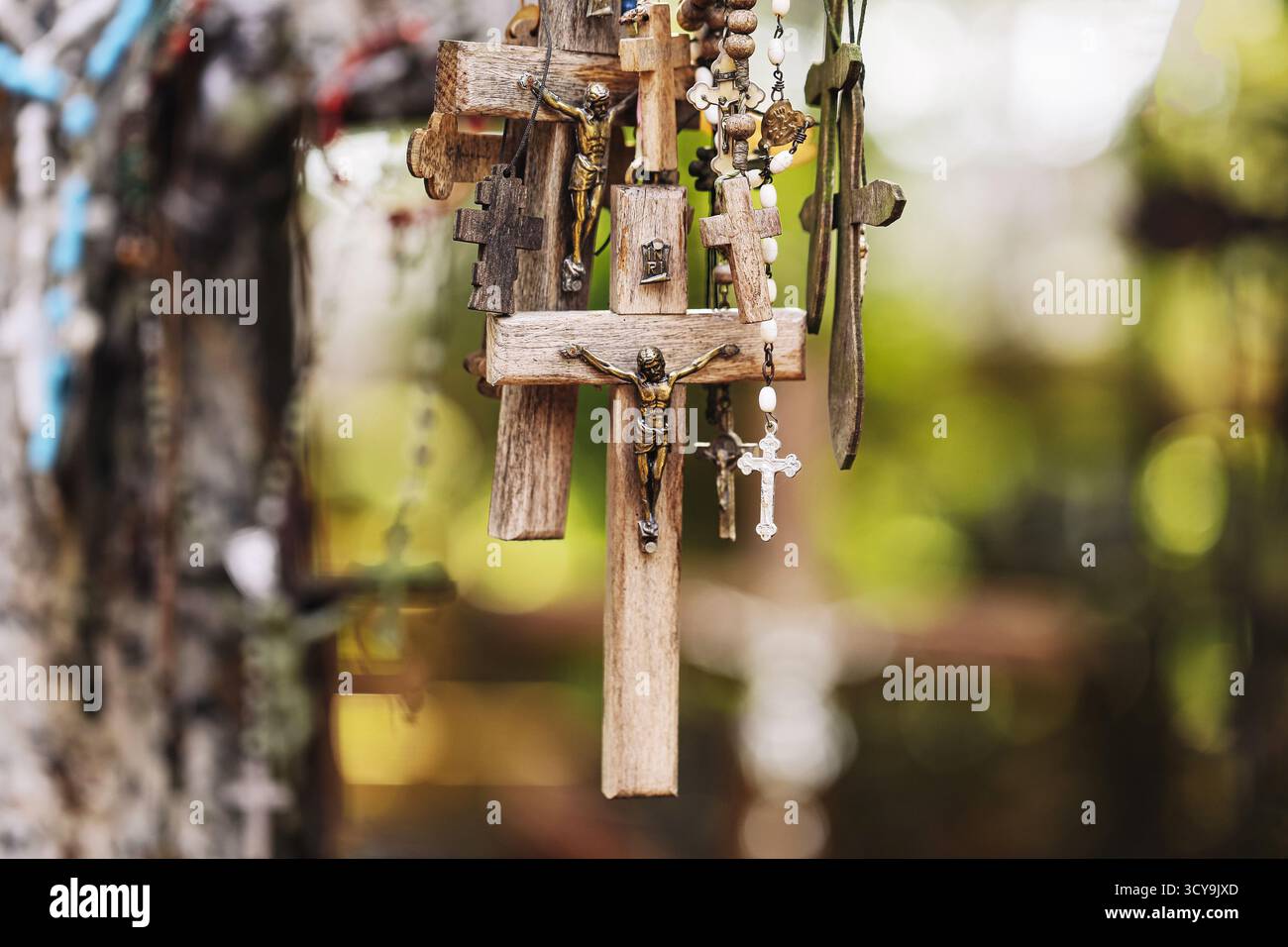 Croce in legno con rosario all'aperto. Simbolo religioso in natura. Fede cristiana e concetto di spiritualità. Dettaglio devozionale del cimitero. Foto Stock