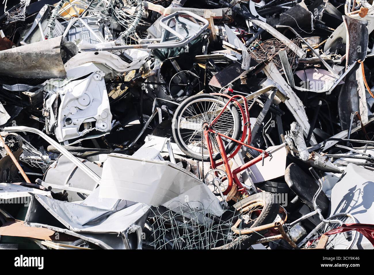 Rottamare il cumulo di metallo con parti di biciclette. Mucchio di oggetti metallici schiacciati e macchine rotte. Background del processo di riciclaggio industriale. Rifiuti ambientali. Foto Stock