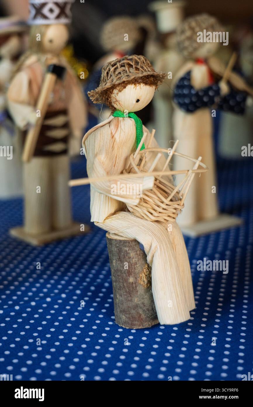 Primo piano di una statuetta di buccia di mais con statuette sfocate sullo sfondo, vista laterale. Foto Stock