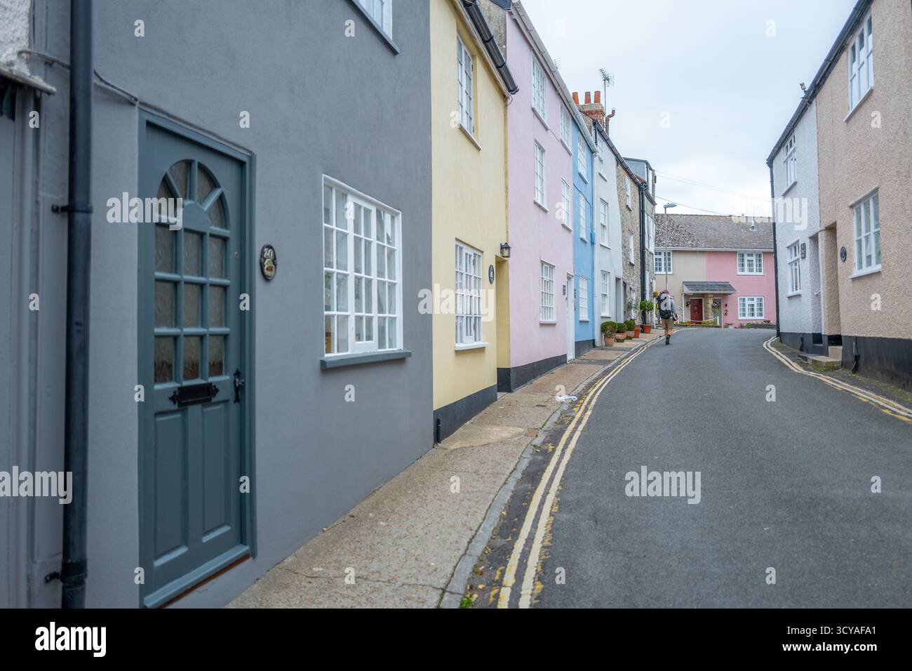 Case dipinte a pastello lungo la stretta corsia e dipinte di giallo sul parcheggio a doppia linea Mill Green nella città balneare di Lyme Regis, Dorset. Foto Stock