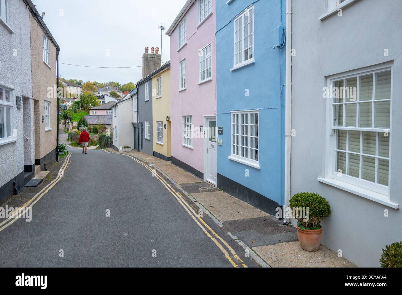 Case dipinte a pastello lungo la stretta corsia e dipinte di giallo sul parcheggio a doppia linea Mill Green nella città balneare di Lyme Regis, Dorset. Foto Stock