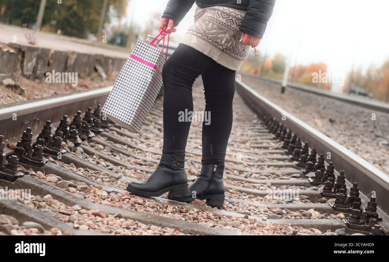 Una donna che porta con sé un sacchetto di carta per la spesa regalo, i binari del trenino Foto Stock