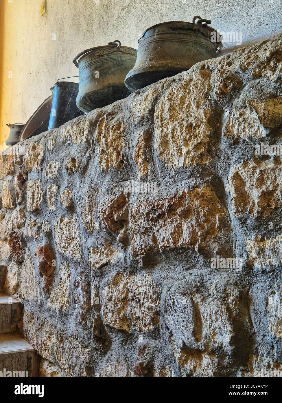 vecchie pentole di metallo in piedi su un muro di pietra. il muro è fatto di pietra grezza. stile storico rustico - Immagine stock catturata con smartphone