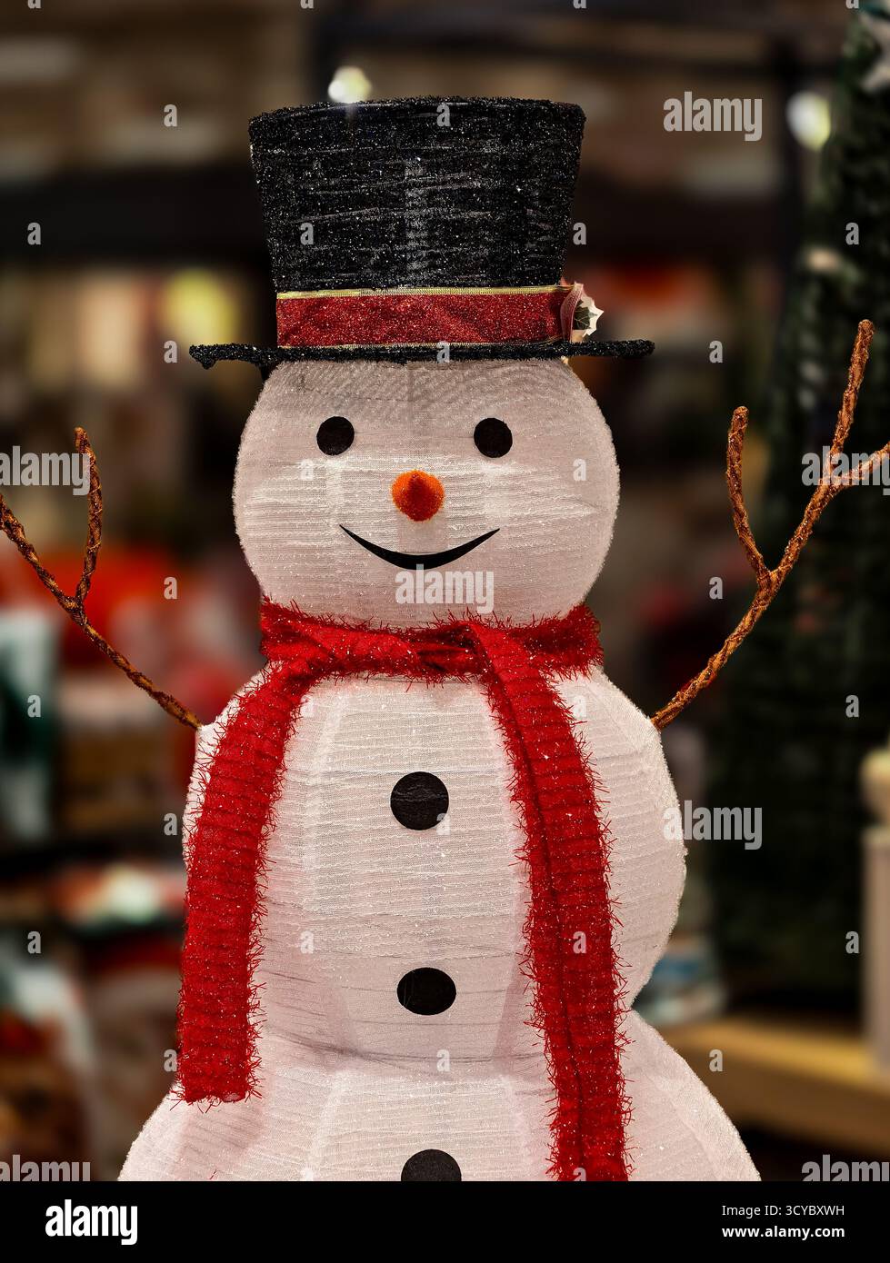 Affascinante pupazzo di neve sorridente con cappello nero e sciarpa rossa in un negozio natalizio. Foto di scorta professionale per il marketing e l'arredamento natalizio Foto Stock