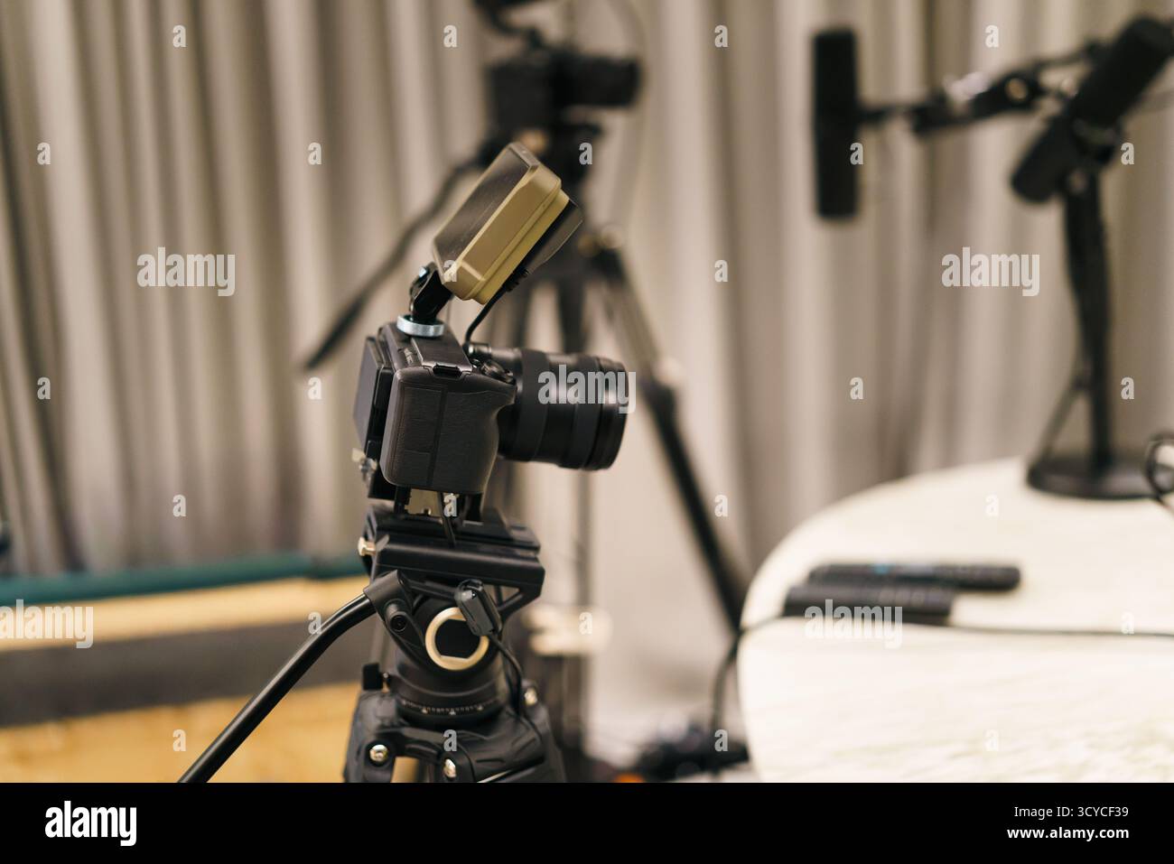 Configurazione del microfono Podcast da studio su treppiede con telecomando su tavolo rotondo in tenda morbida, ambiente professionale per aud video Foto Stock