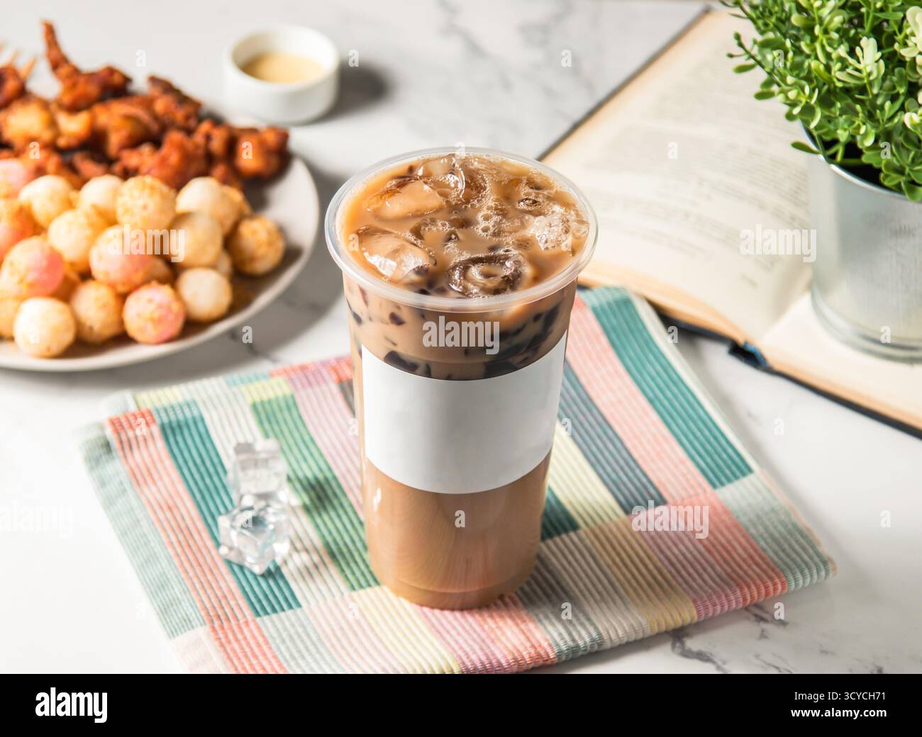 Tè al latte gelato con boba e cubetto di ghiaccio servito in vetro di plastica con cubetto di ghiaccio isolato sul tovagliolo vista laterale della bevanda fredda di taiwan Foto Stock