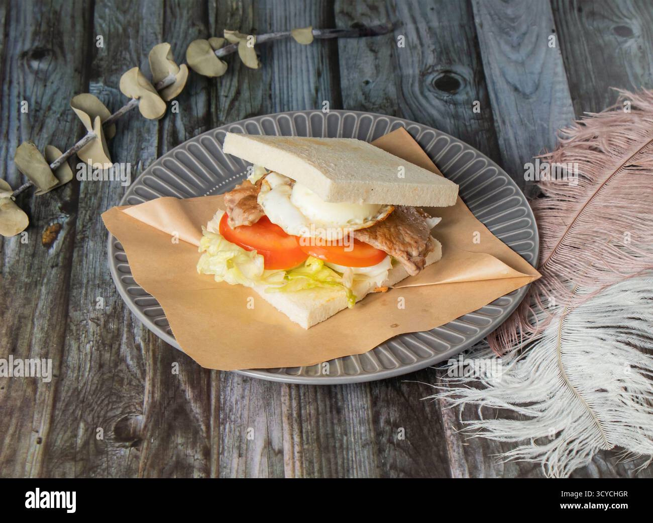 Colazione taiwanese, sandwich a base di carne e toast all'uovo con pomodoro e cavolo serviti in piatti isolati su sfondo in legno, vista laterale del cibo di taiwan Foto Stock