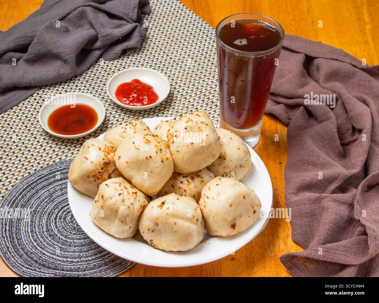 Panini fritti in padella da 10 pezzi con salse da immersione e un alto bicchiere di tè freddo isolato sul tovagliolo vista laterale del cibo dim sum di taiwan Foto Stock
