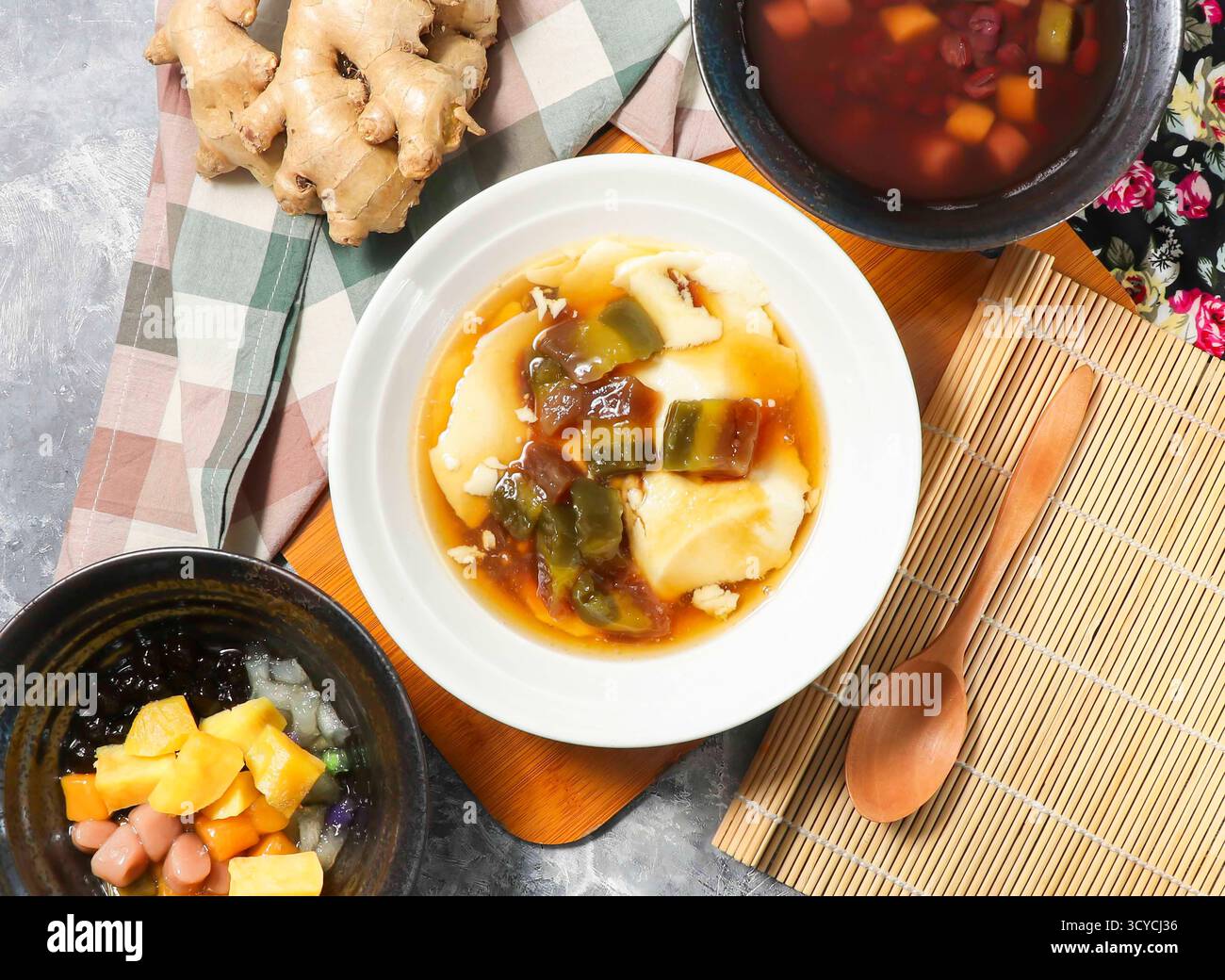 Il budino di tofu taiwanese include budino di tofu setoso, zuppa di patate dolci e gelatine di frutta rinfrescanti servite in brodo con cucchiaio isolato su una tavola di legno Foto Stock