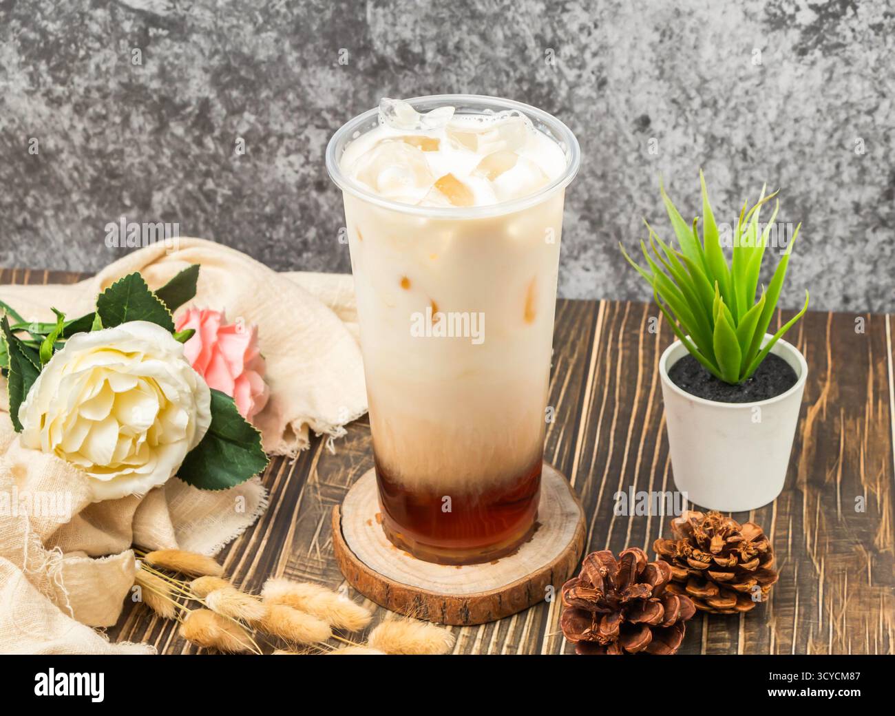 Tè nero al latte fresco freddo con cubetti di ghiaccio servito in vetro usa e getta, con vista laterale della bevanda taiwanese Foto Stock