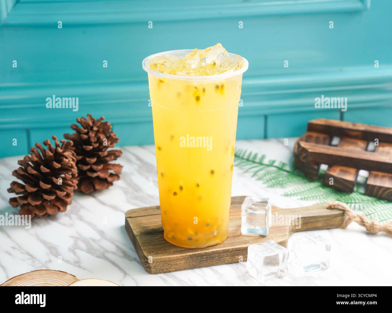 Tè verde freddo alla frutta della passione con cubetti di ghiaccio in alto vetro servito su una tavola di legno con vista laterale della bevanda fredda di taiwan Foto Stock