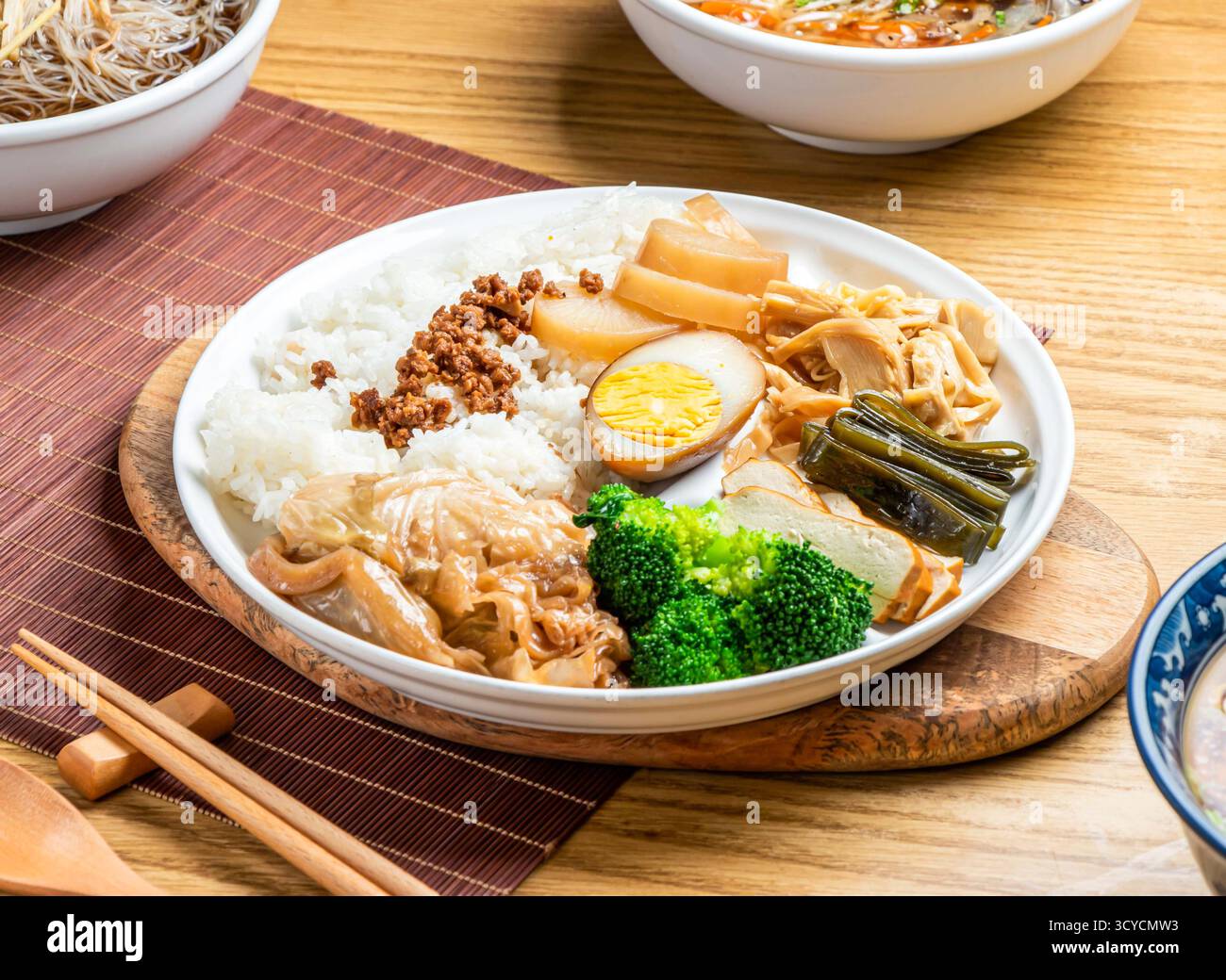 i fan taiwanesi lu rou includono riso, broccoli, uova sode, tofu, maiale macinato, pancetta di maiale brasata e cavolo servito nel piatto con bacchette e cucchiaio Foto Stock