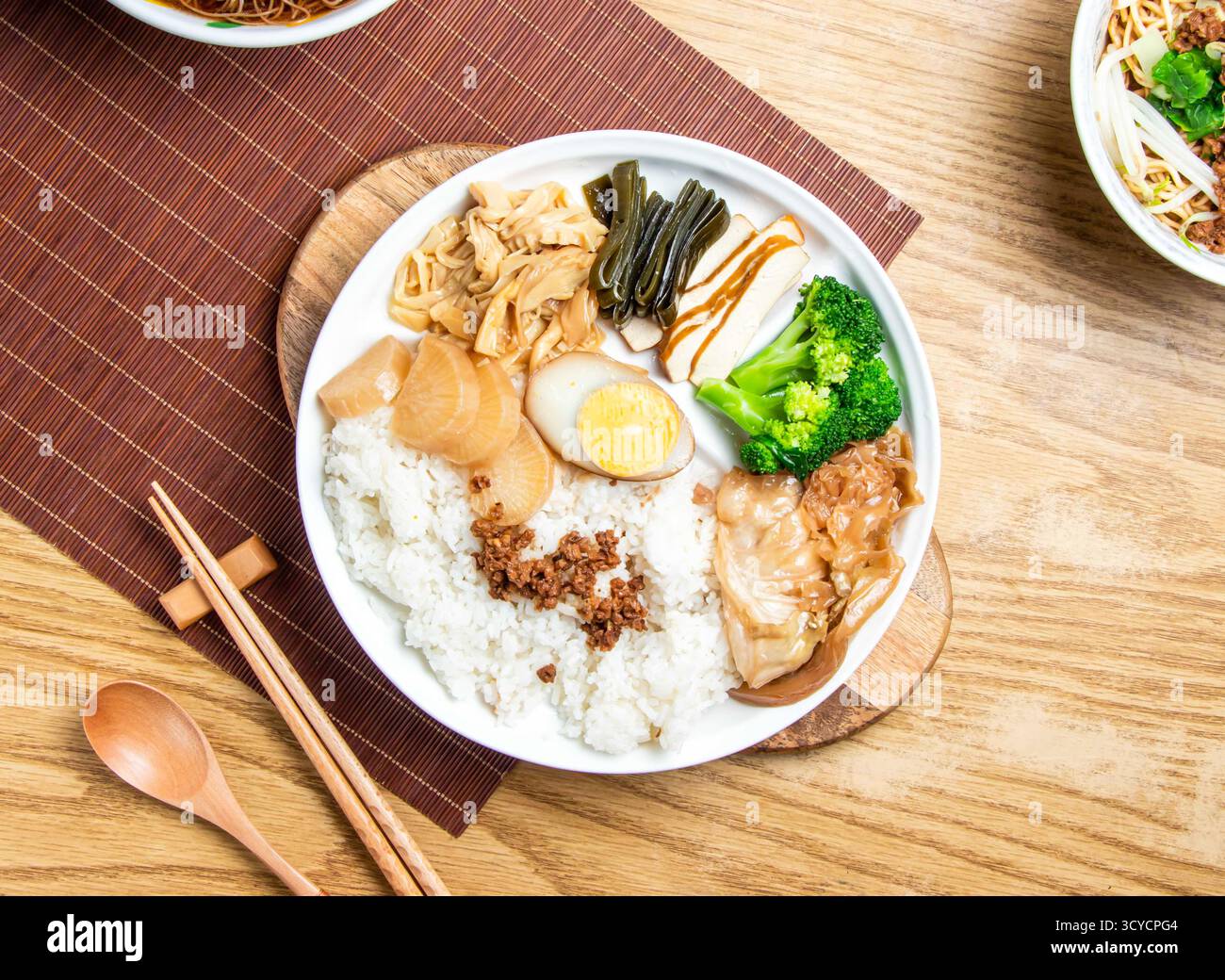 i fan taiwanesi lu rou includono riso, broccoli, uova sode, tofu, maiale macinato, pancetta di maiale brasata e cavolo servito nel piatto con bacchette e cucchiaio Foto Stock