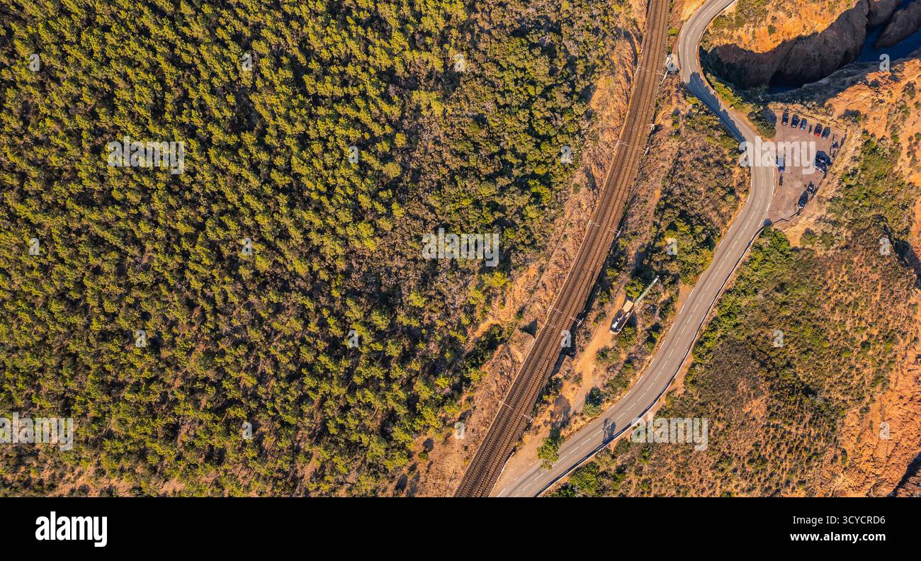 Vista aerea panoramica della costa dei monti Esterel con tortuose strade costiere e binari ferroviari che sovrastano il Mar Mediterraneo, la Costa Azzurra e il Sud Foto Stock