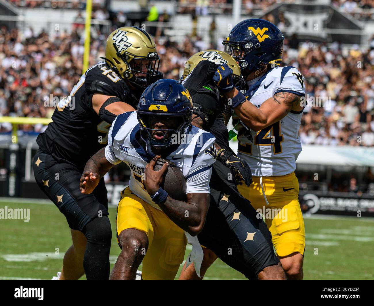 Orlando, Florida, Stati Uniti. 18 ottobre 2025. Il quarterback dei West Virginia Mountaineers Khalil Wilkins (14) esegue la palla per un tocco in giù nel primo tempo durante il football NCAA contro gli UCF Knights all'Acrisure Bounce House di Orlando, Florida. Romeo T Guzman/CSM/Alamy Live News Foto Stock