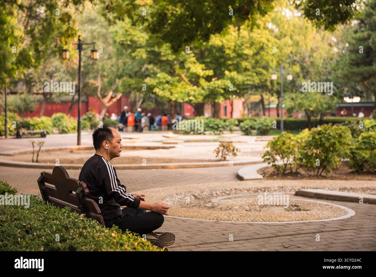 Pechino, Cina - 5 ottobre 2018: Uomo asiatico che medita sulla panchina nel giardino Zen nel parco Ritan, un parco pubblico situato nel distretto di Chaoyang Foto Stock