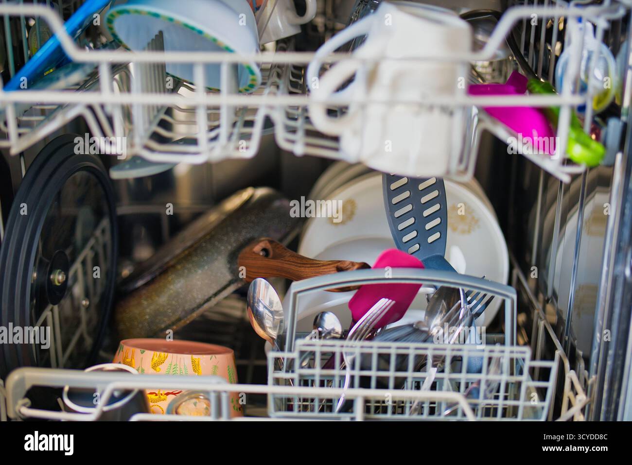 Vista interna della lavastoviglie carica con stoviglie, utensili e pentole assortiti pronti per il ciclo di pulizia Foto Stock
