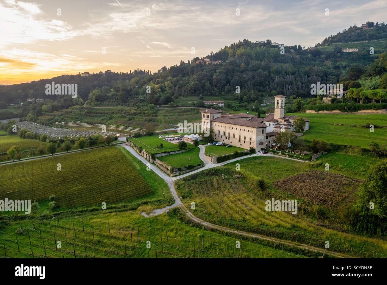 Veduta aerea del Monastero di Astino vicino a Bergamo, Lombardia, Italia. Paesaggio panoramico dei vigneti al tramonto, monastero storico e turismo rurale destinati Foto Stock