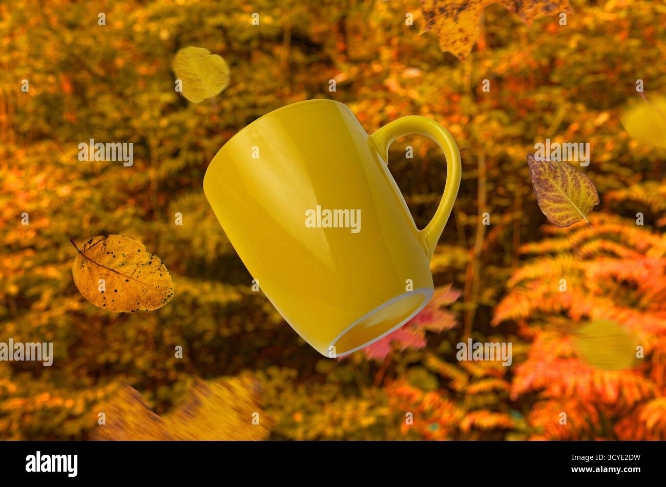 Tazza da caffè gialla circondata da foglie cadenti e da una foresta dorata calda, perfetta idea autunnale per design e pubblicità Foto Stock