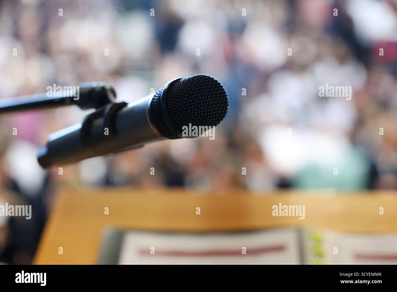 Un unico microfono nero isolato su una conferenza sfocata e sullo sfondo delle persone o del pubblico. Discorso pubblico, paura e discorsi tema. Persona Foto Stock