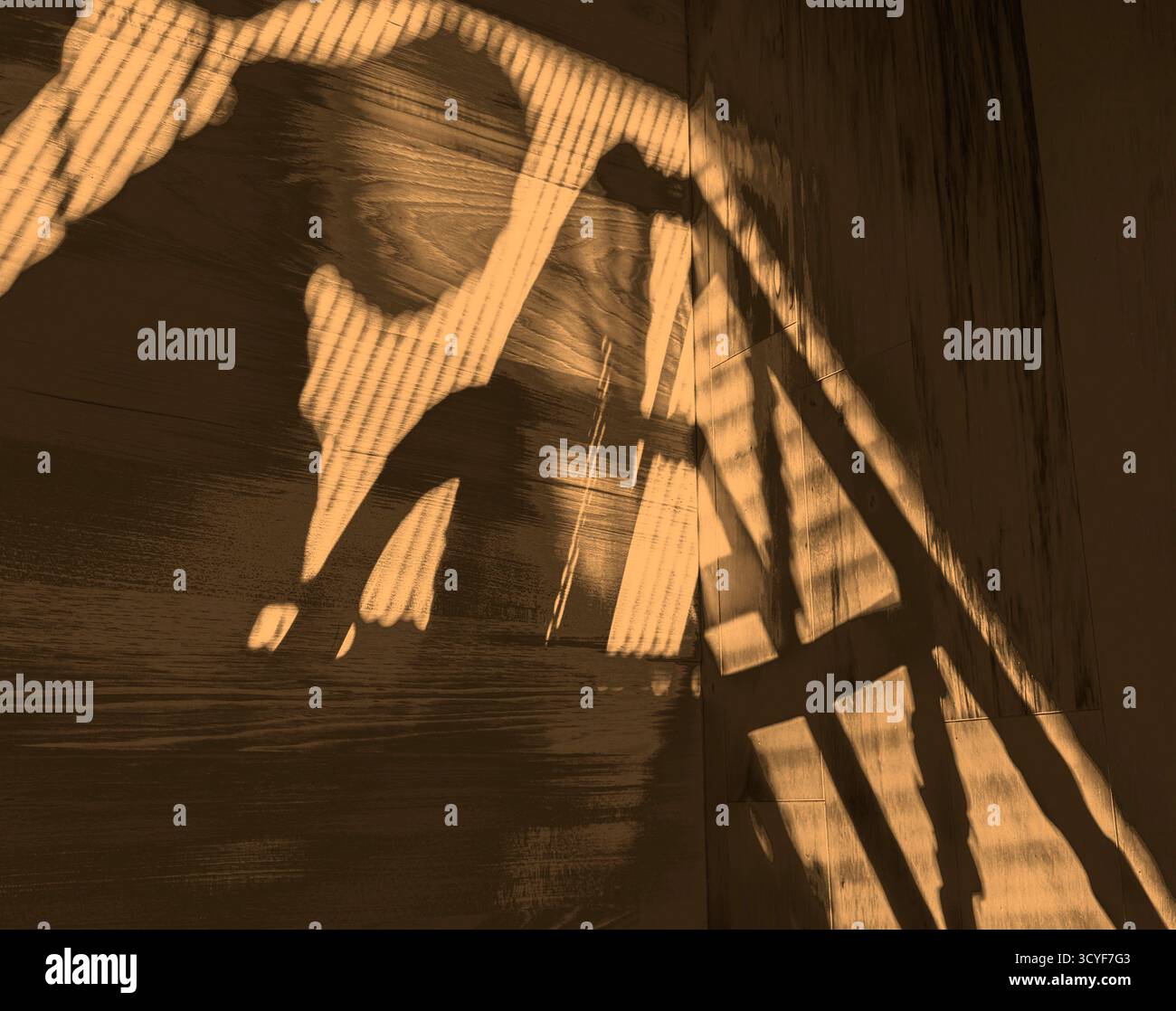 Un'immagine d'ombra mostra una figura spettrale al piano superiore in soffitta che lavora al monitor o dipinge un'immagine. Lo sfondo è a grana di legno con ombre profonde su rotaia. Foto Stock