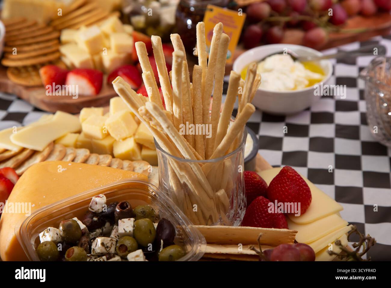 Vista di un tagliere di formaggi, con un bicchiere di grissini tostati. Foto Stock