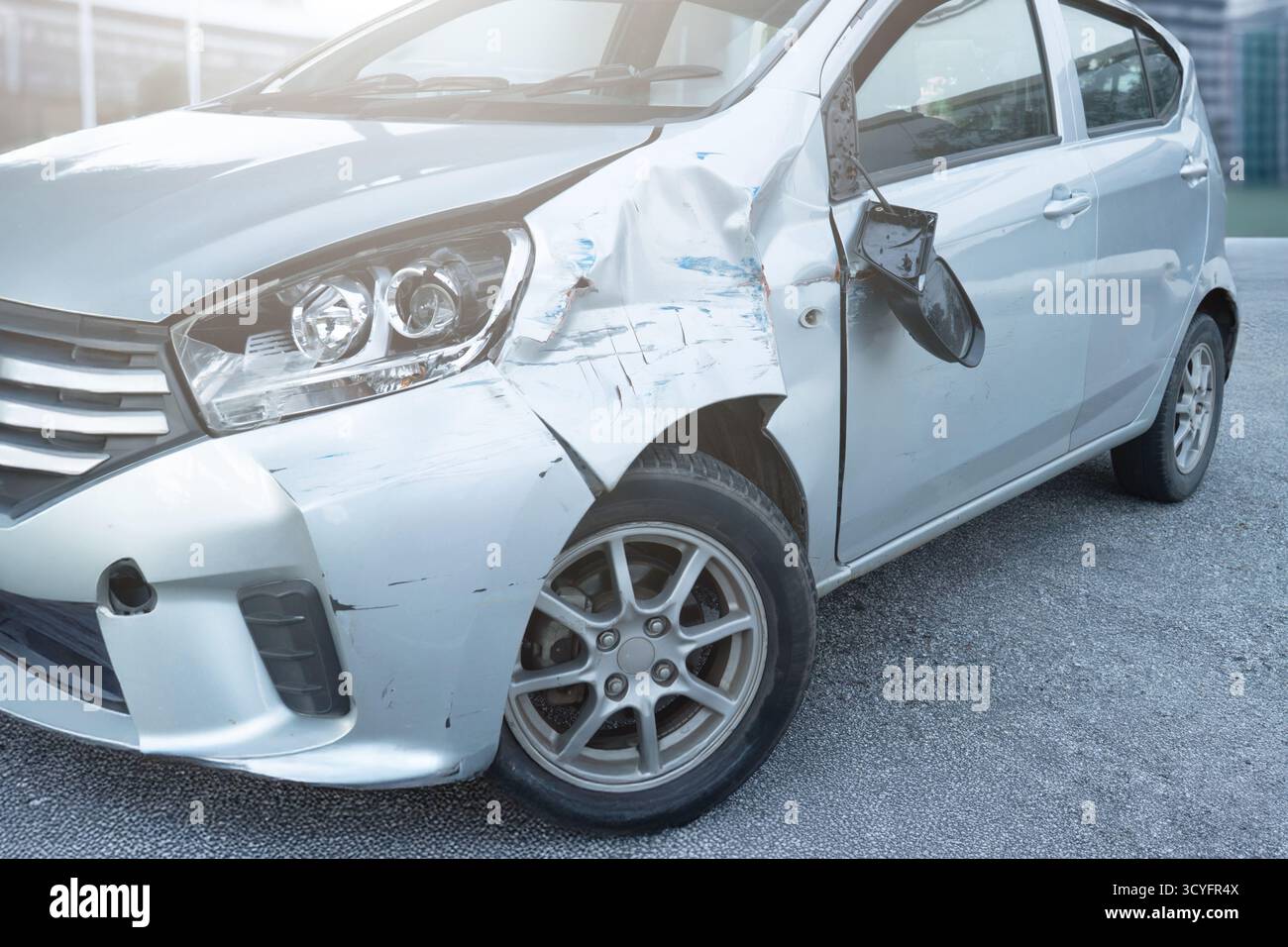 Vista laterale anteriore di una vettura con danni visibili e ammaccature dopo un incidente. Crash del veicolo, reclamo assicurativo, sicurezza stradale e concetto di riparazione dell'auto. Foto Stock