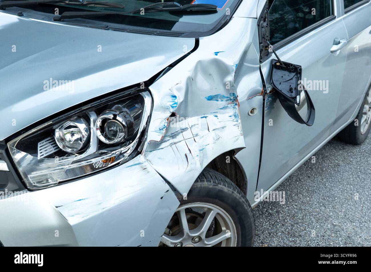 Vista laterale anteriore di una vettura con danni visibili e ammaccature dopo un incidente. Crash del veicolo, reclamo assicurativo, sicurezza stradale e concetto di riparazione dell'auto. Foto Stock
