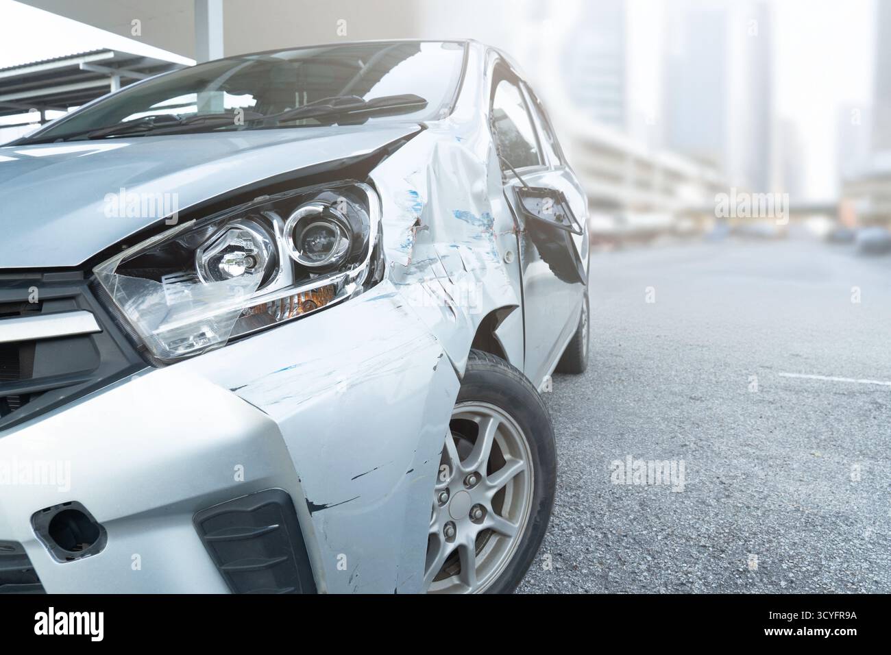 Vista laterale anteriore di una vettura con danni visibili e ammaccature dopo un incidente. Crash del veicolo, reclamo assicurativo, sicurezza stradale e concetto di riparazione dell'auto. Foto Stock